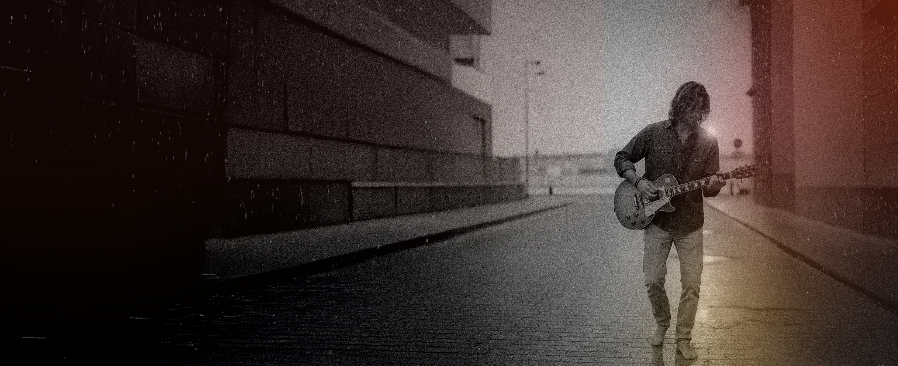 Ian Vanez walking with a guitar